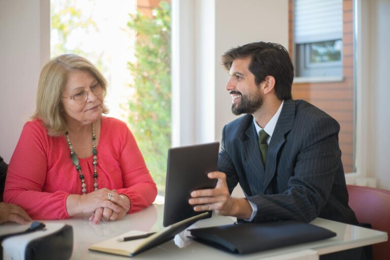 Elderly woman consulting with a realtor about a property deal in a cozy indoor setting.